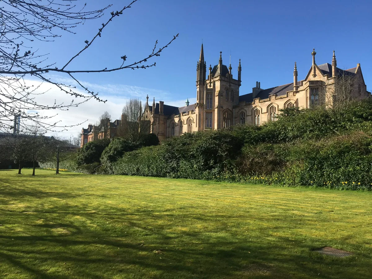 A gothic-spired building across a sunlit lawn